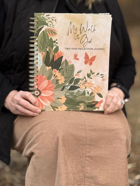 KJV Prayer Journal for Women video showing beautiful floral design with lush greenery and shades of pink and peach florals and butterflies.  The gold metal spiral binding to lay flat and hard back covers designed for ease of writing,  The 8.5"x11" Self Reflection Journaling book offers a silk and band book mark to hold your place during your two years of use provided by Kinsman & Company.  